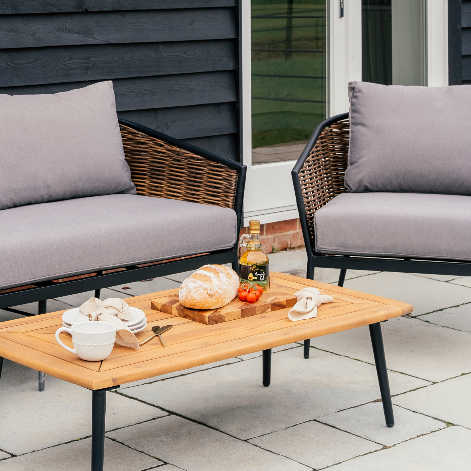 Contemporary outdoor seating area with rattan-style garden furniture, wooden coffee table, and casual dining setup